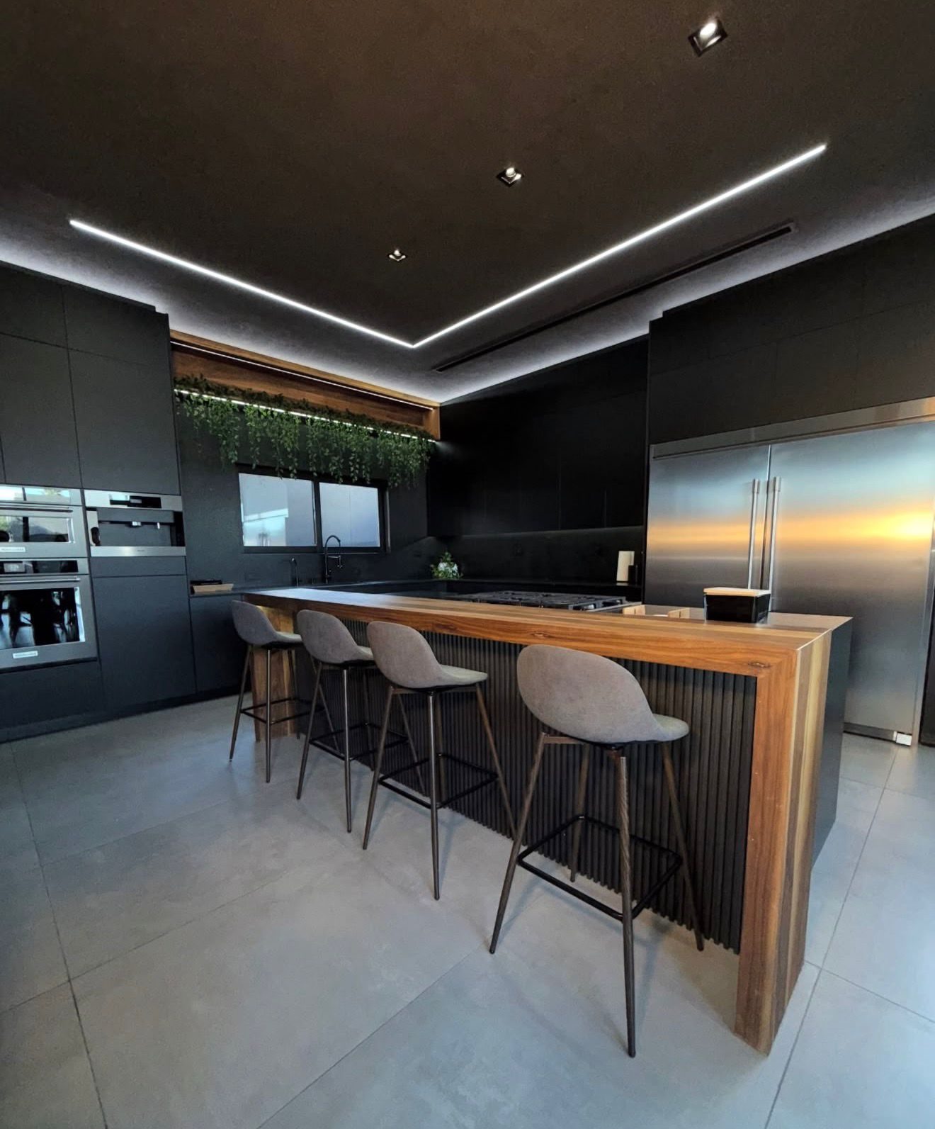 Cocina Corderosa oscura con barra de madera e iluminación lineal