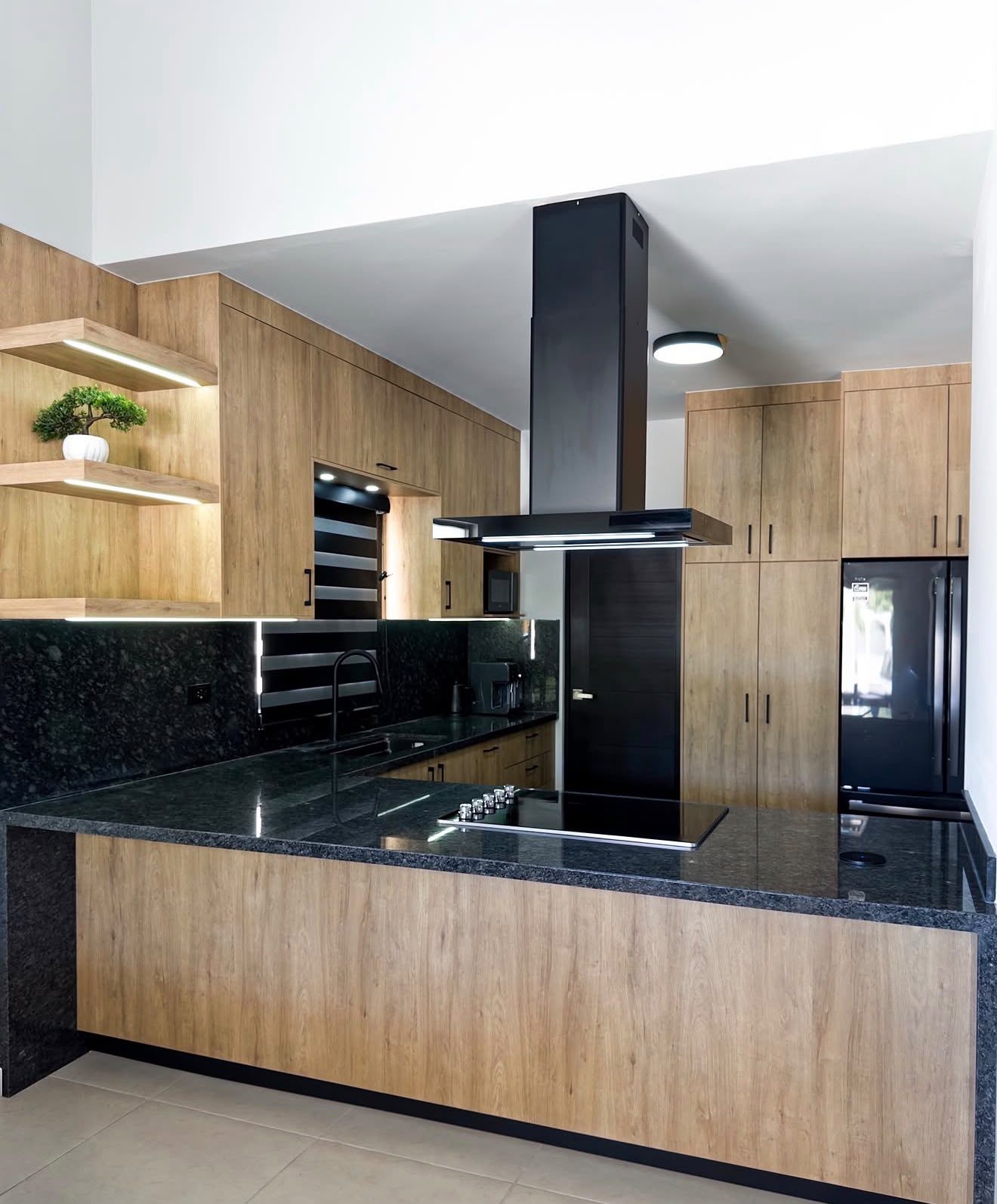 Cocina Corderosa en madera con cubierta de granito verde y campana negra